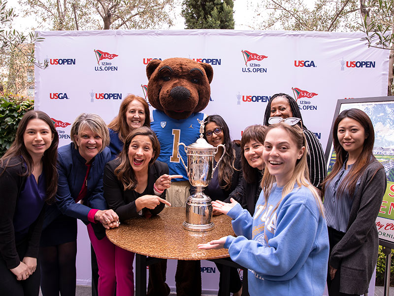 Members of UCLA's hospitality units pose with the USGA open trophy